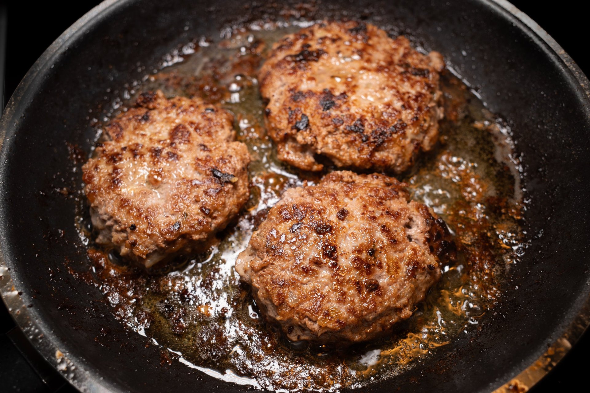 Beef patties sizzling in golden butter